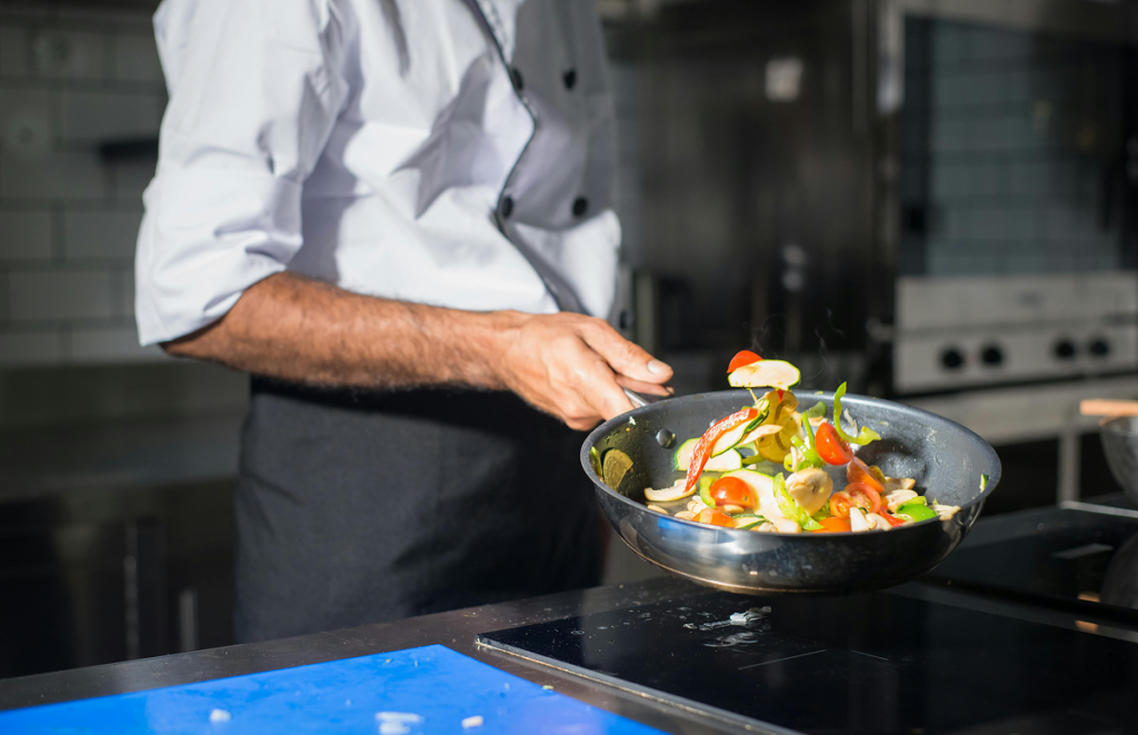 Cozinheiro usando frigideira. Graduação em culinária.
