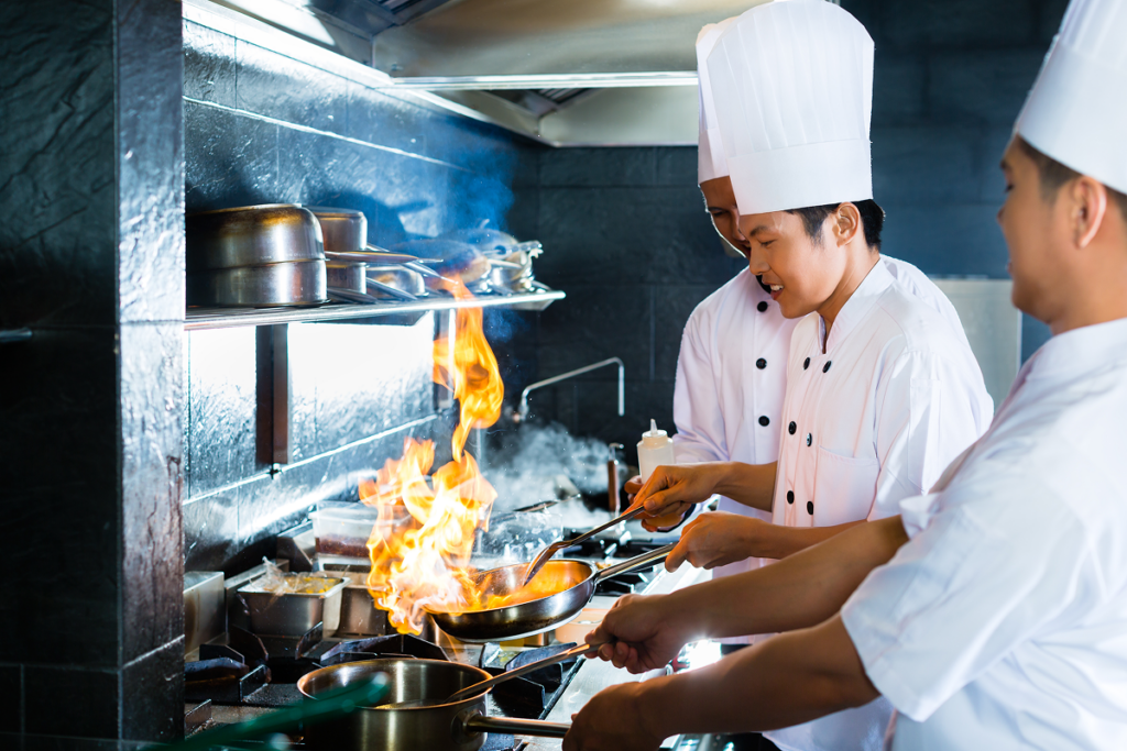 Cozinheiros trabalham em fogão de cozinha. Graduação em culinária.