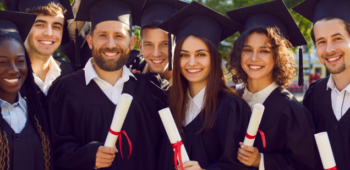 grupo de jovens vestidos de formandos, segurando seus diplomas e sorrindo. Graduação tecnológica.