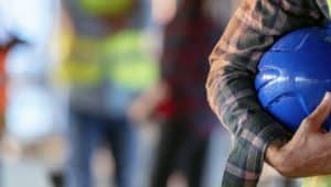 mão com capacete representando segurança no trabalho