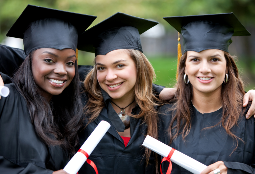 Três mulheres vestidas de formandas, segurando seus diplomas. Como conseguir bolsa para segunda graduação.