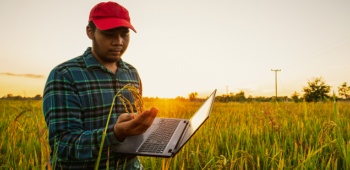 Homem andando por plantação e carregando um computador. Características pessoais que devo ter para ser um agrônomo