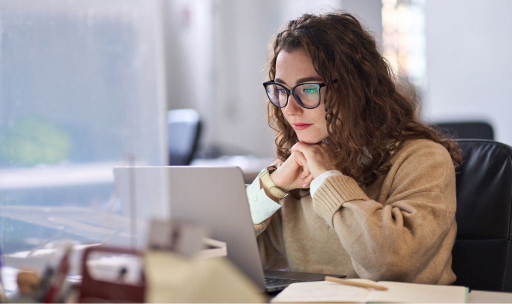 Mulher olhando para o computador e pensando. Diferença entre especialização e pós graduação.