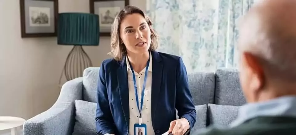 Mulher ouvindo idoso e anotando informações em caderno