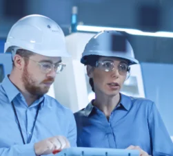 Homem e mulher analisando maquinário em fábrica