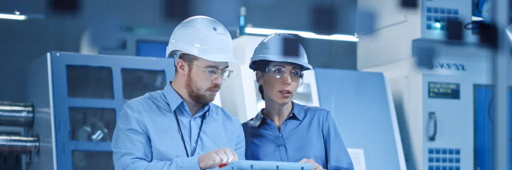 Homem e mulher analisando maquinário em fábrica