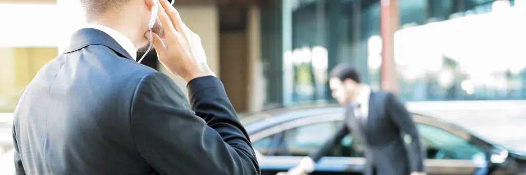 Segurança falando em fone e esperando alguém sair do carro