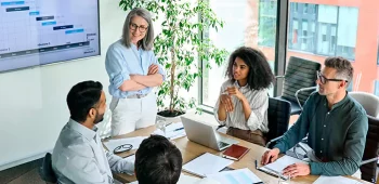 Pessoas reunidas em escritório apresentando dados