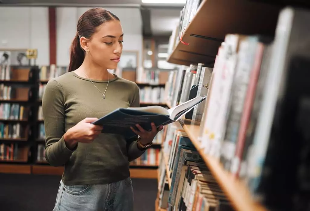 Moça lendo livro em biblioteca
