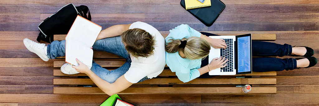 Estudantes sentados em banco de faculdade