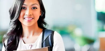 Moça em faculdade com mochila e segurando livro