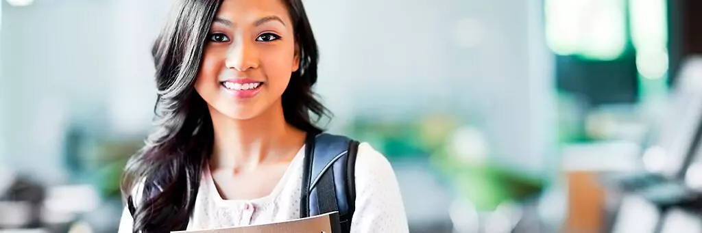 Moça em faculdade com mochila e segurando livro
