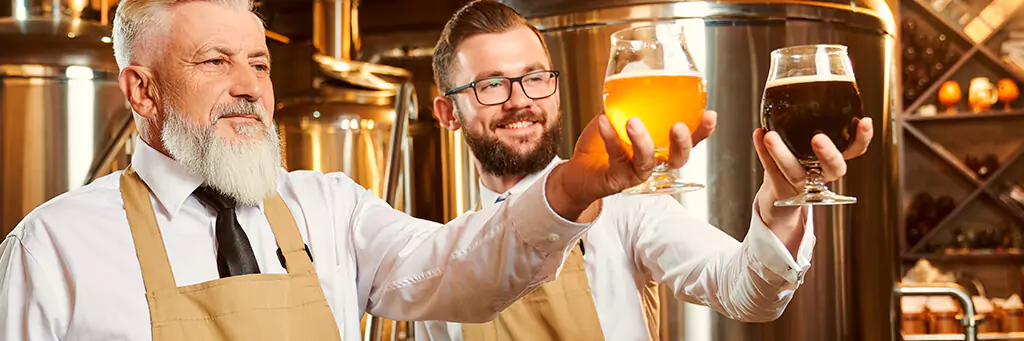 Dois cervejeiros analisando copos de cerveja