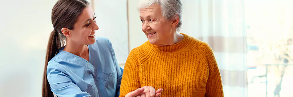 moça sorridente ajudando mulher idosa