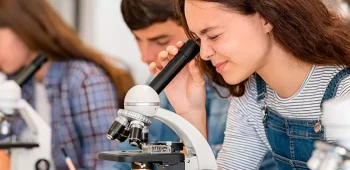 estudantes olhando em microscópio em sala de aula