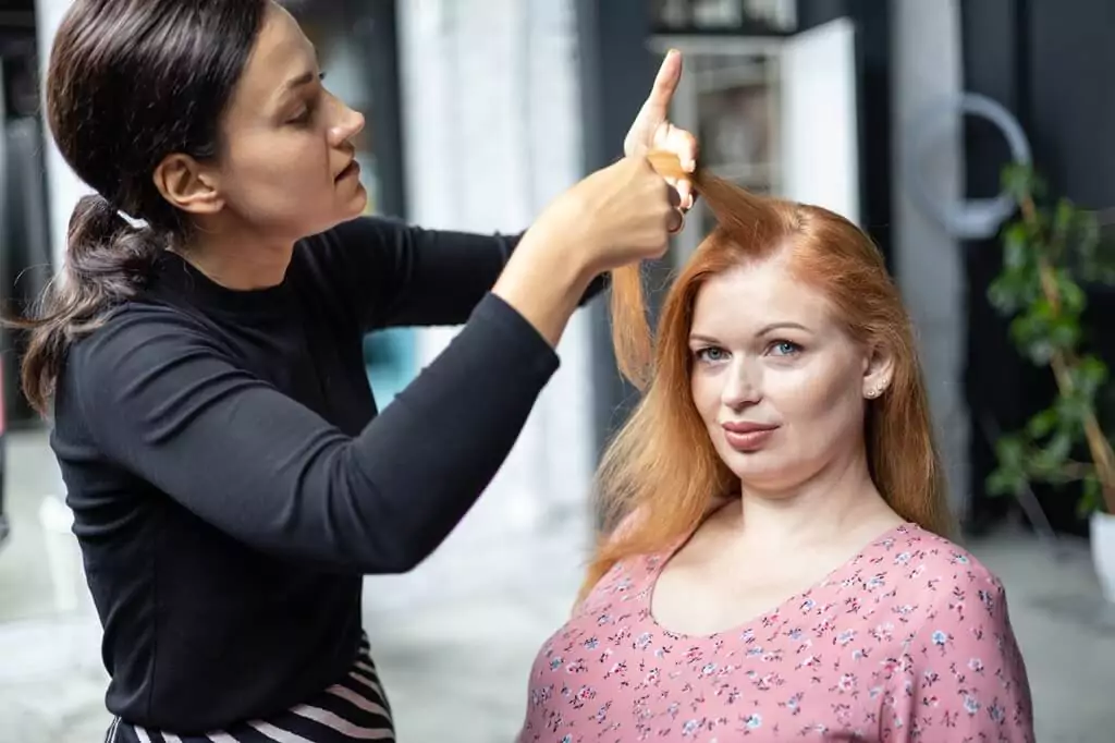 mulher cuidando do cabelo de cliente em salão