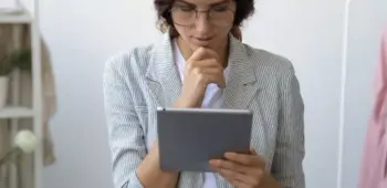 mulher olhando tablet em ateliê de roupas