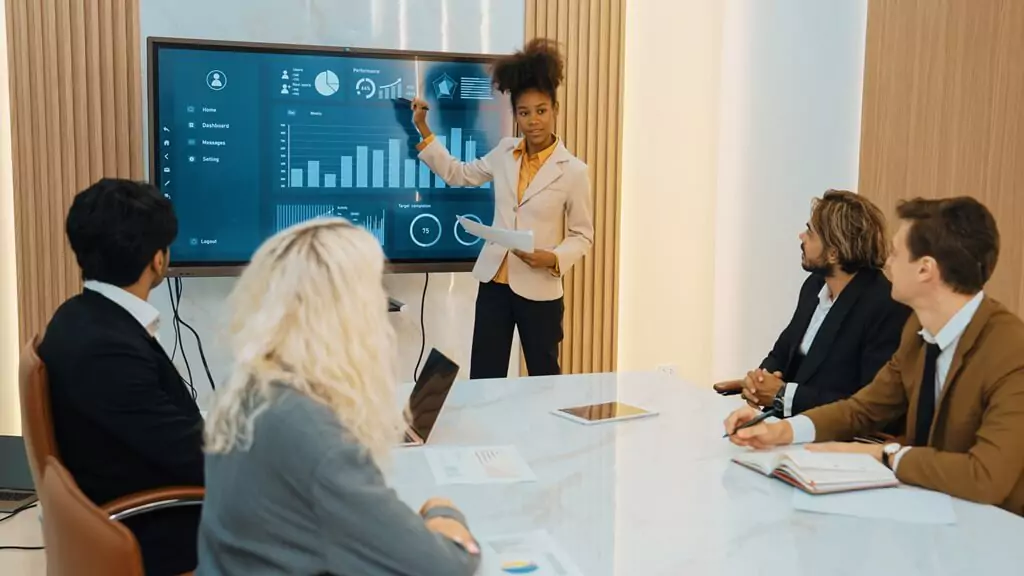 mulher fazendo apresentação de gráficos para pessoas em reunião