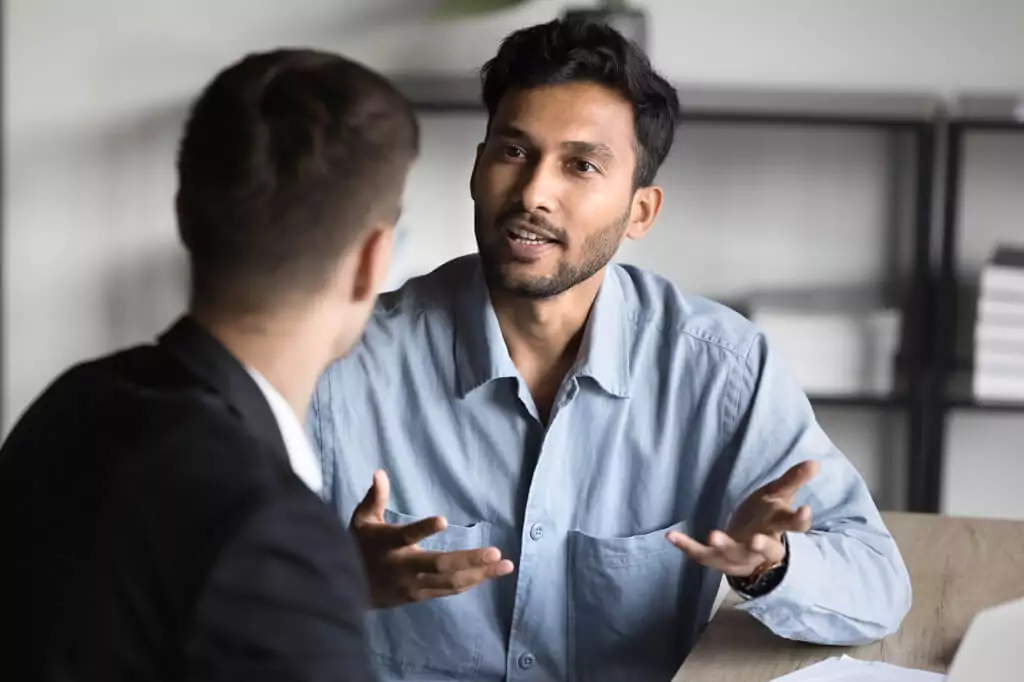 homem explicando algo para rapaz ao seu lado em escritório