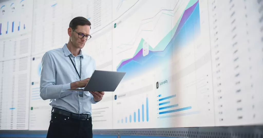 homem ao lado de painel com dados gráficos