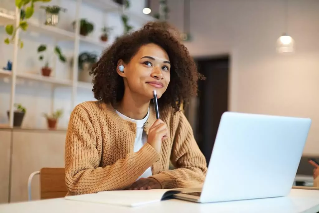 moça pensativa diante de computador e livro