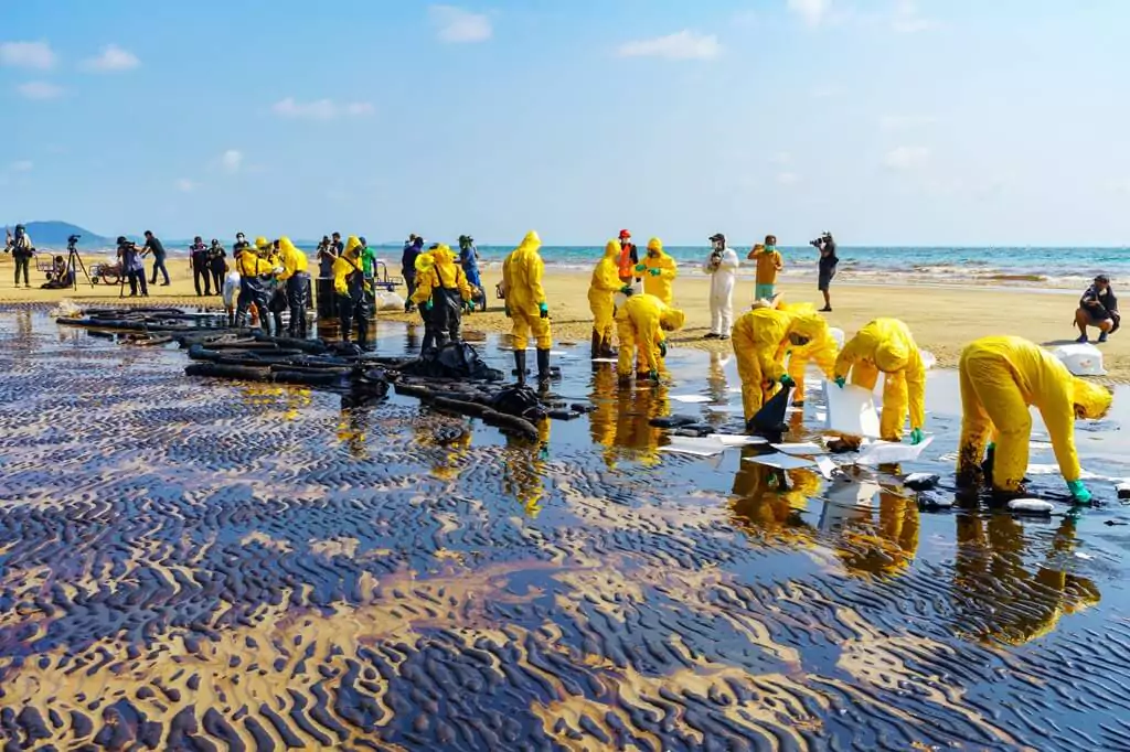 pessoas trabalhando em vazamento de óleo na praia