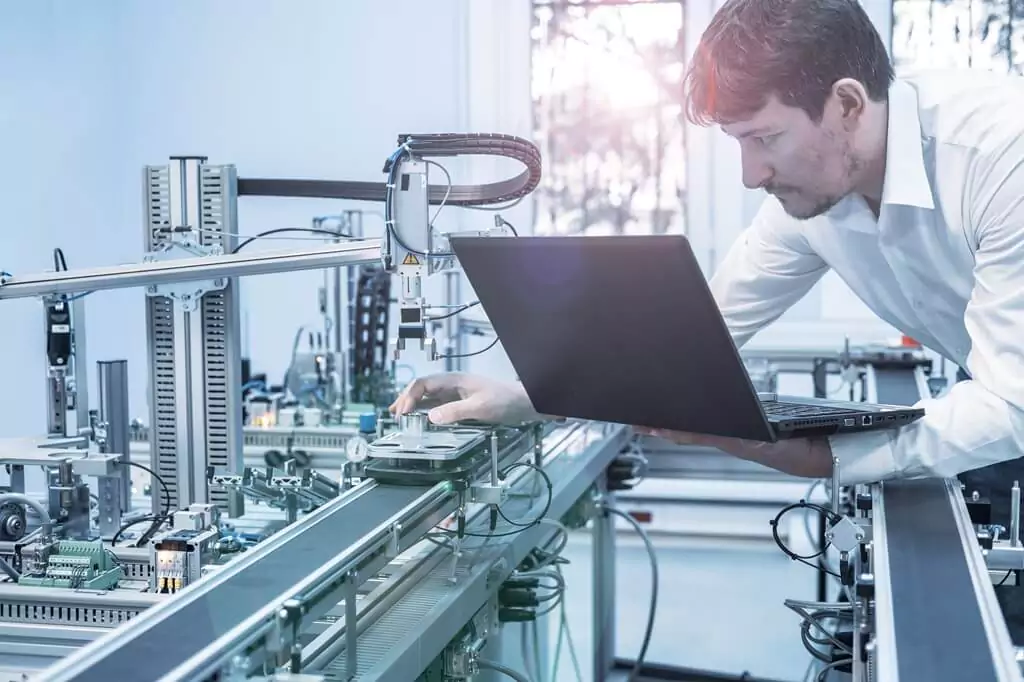 engenheiro com computador monitorando máquina