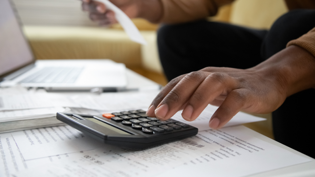 Homem fazendo contas em calculadora. Bolsa de estudo para educação física.
