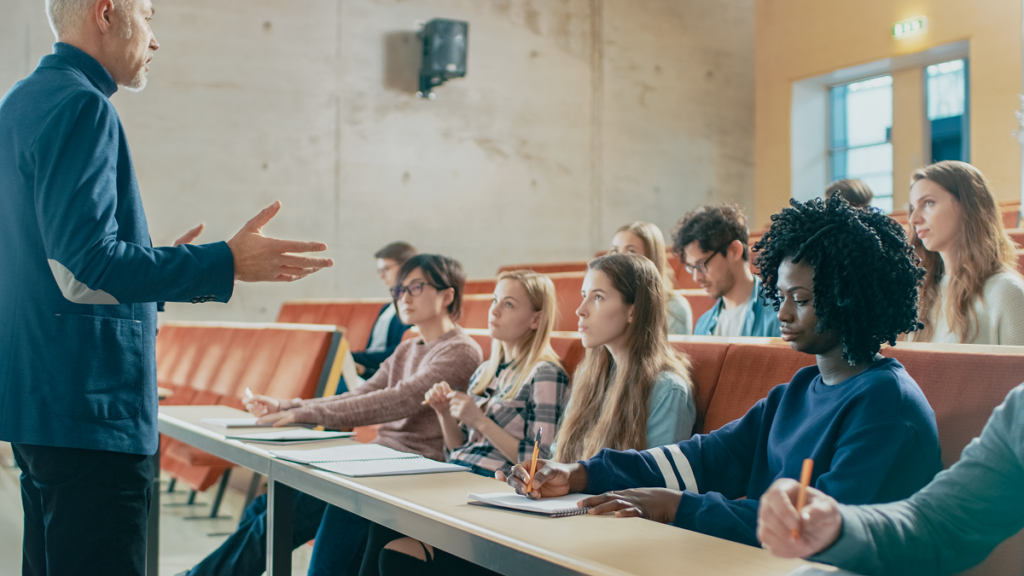 Estudantes escutam professor em sala de aula da pós-graduação em história.