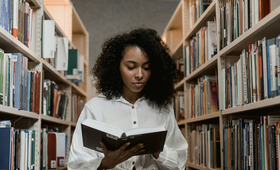 Mulher lendo livro em biblioteca. Pós-graduação em história.