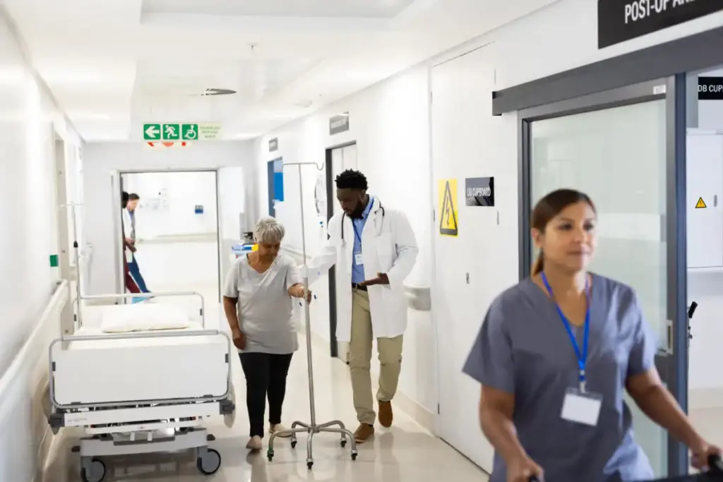 Médico conduzindo paciente idosa pelo corredor do hospital