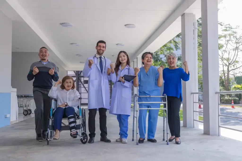 Grupo com médicos e pacientes em clima de celebração na entrada do hospital