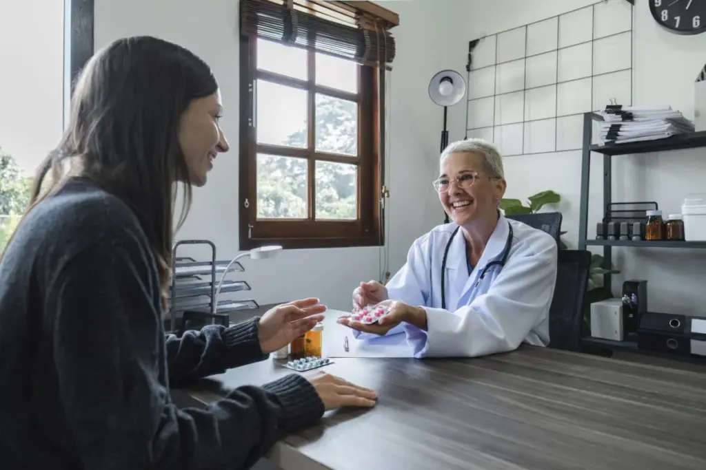 Médica entregando comprimidos à paciente para medicação após consulta de atendimento