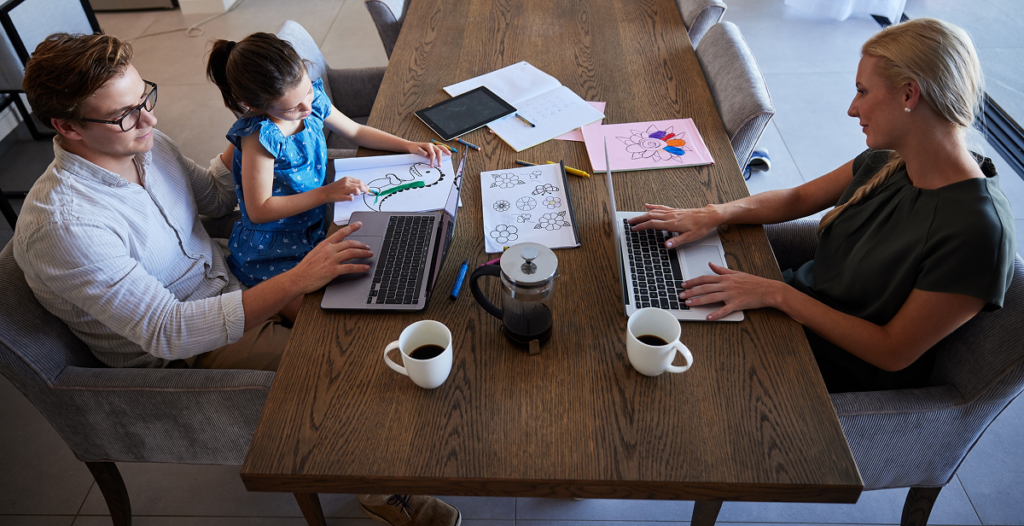 Mãe e pai estudam na mesa de jantar enquanto filho desenha. Graduação em fonoaudiologia ead.