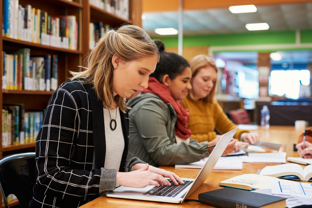 Mulher estudando em biblioteca de universidade. Pós-Graduação em Fonoaudiologia