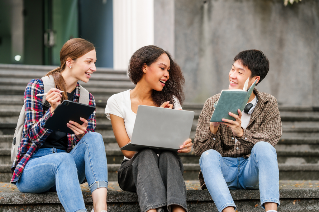 Alunos sentados em escadaria, conversando e estudando. Vale a pena investir no curso de letras português e inglês.