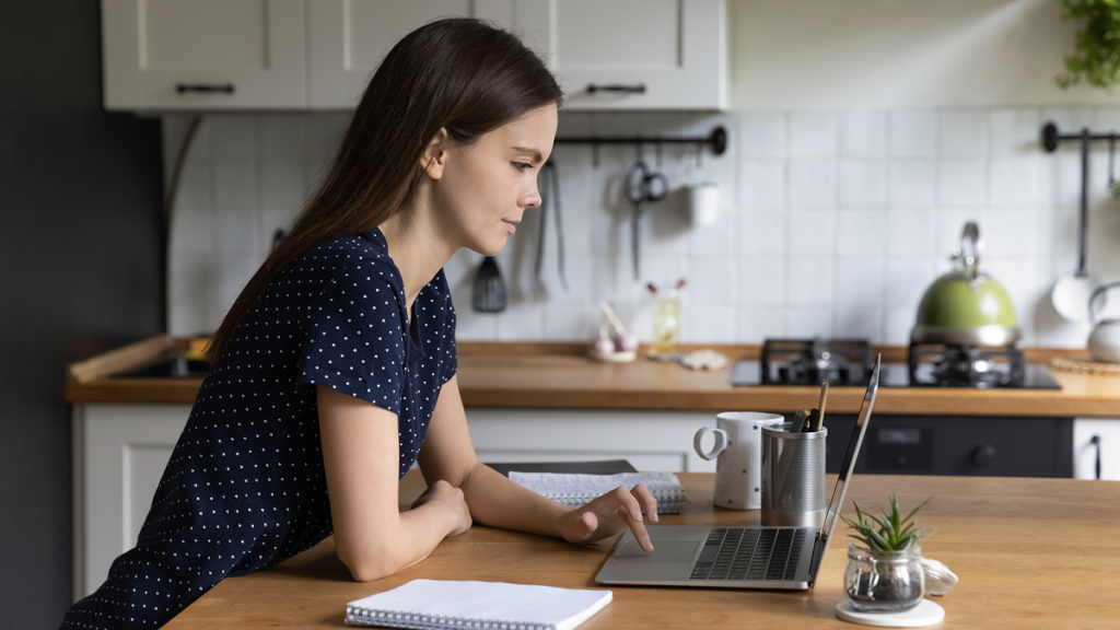 Mulher estudando online na sua cozinha.