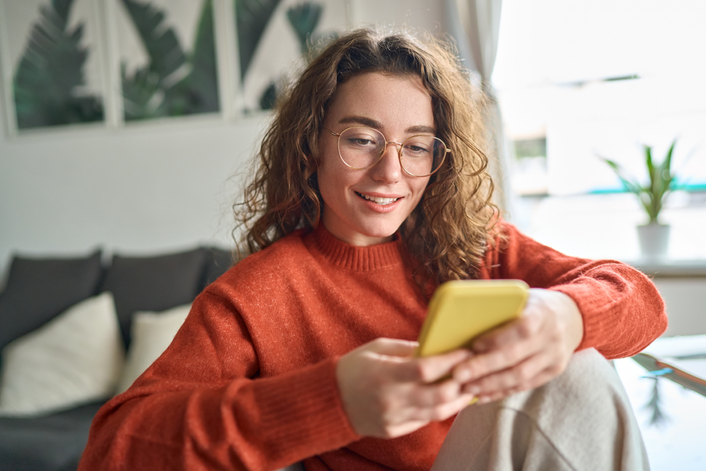 Mulher jovem checando informações no celular.