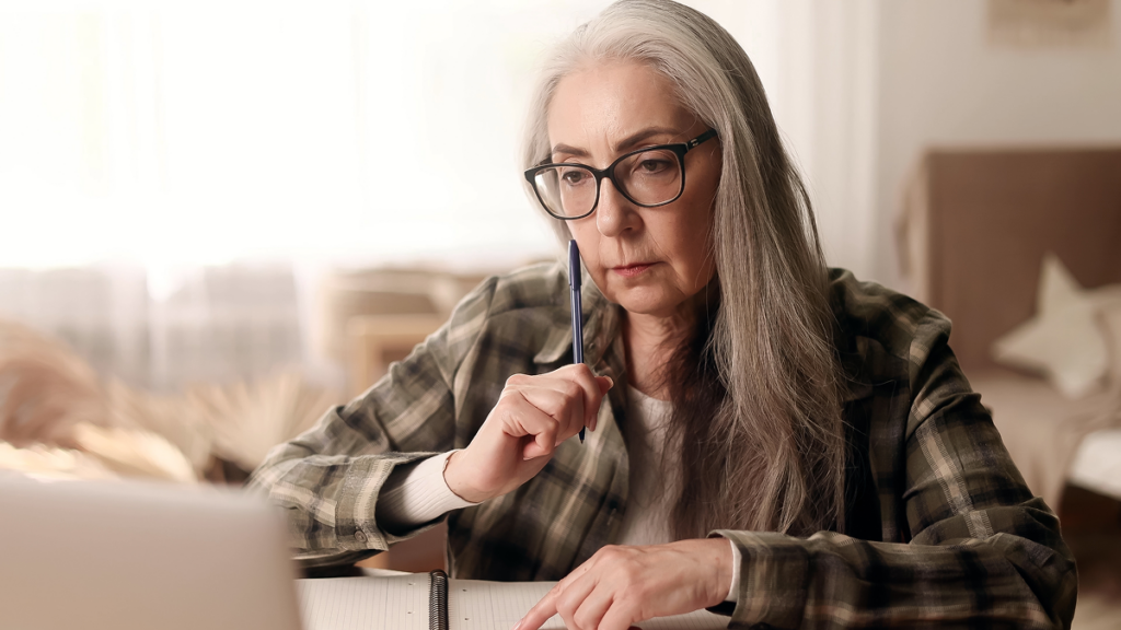 Mulher madura estuda através do computador.