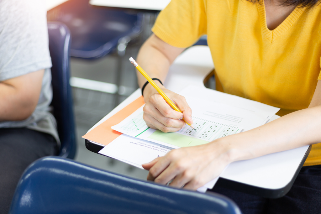 Jovens fazendo prova em sala de aula.