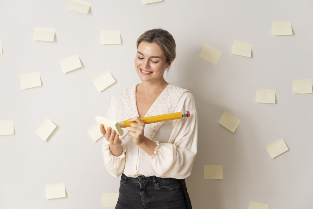 autodesenvolvimento pessoal: mulher segurando um lápis gigante e com vários post its colados na parede